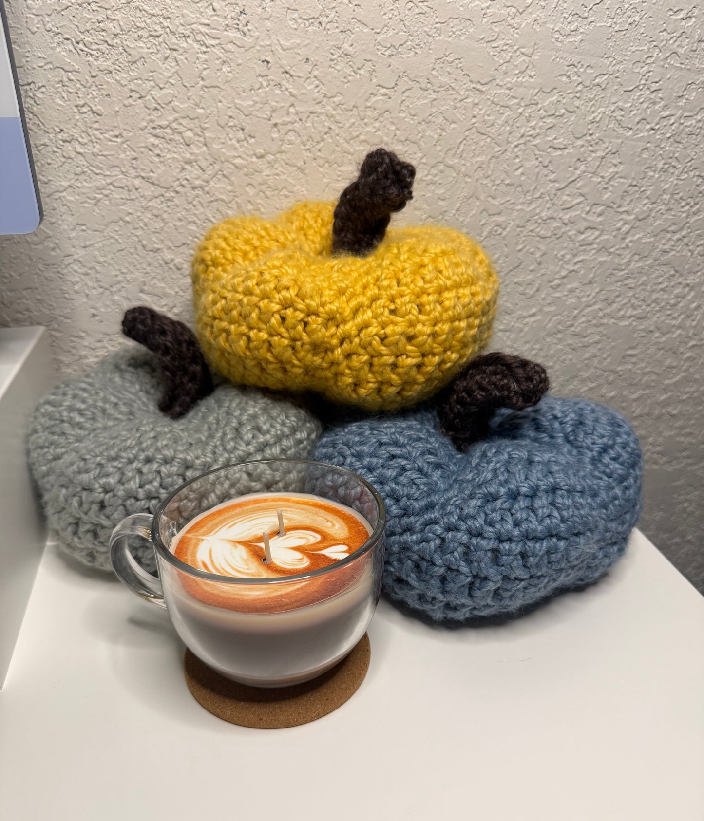 Crochet pumpkins next to a cup of coffee 