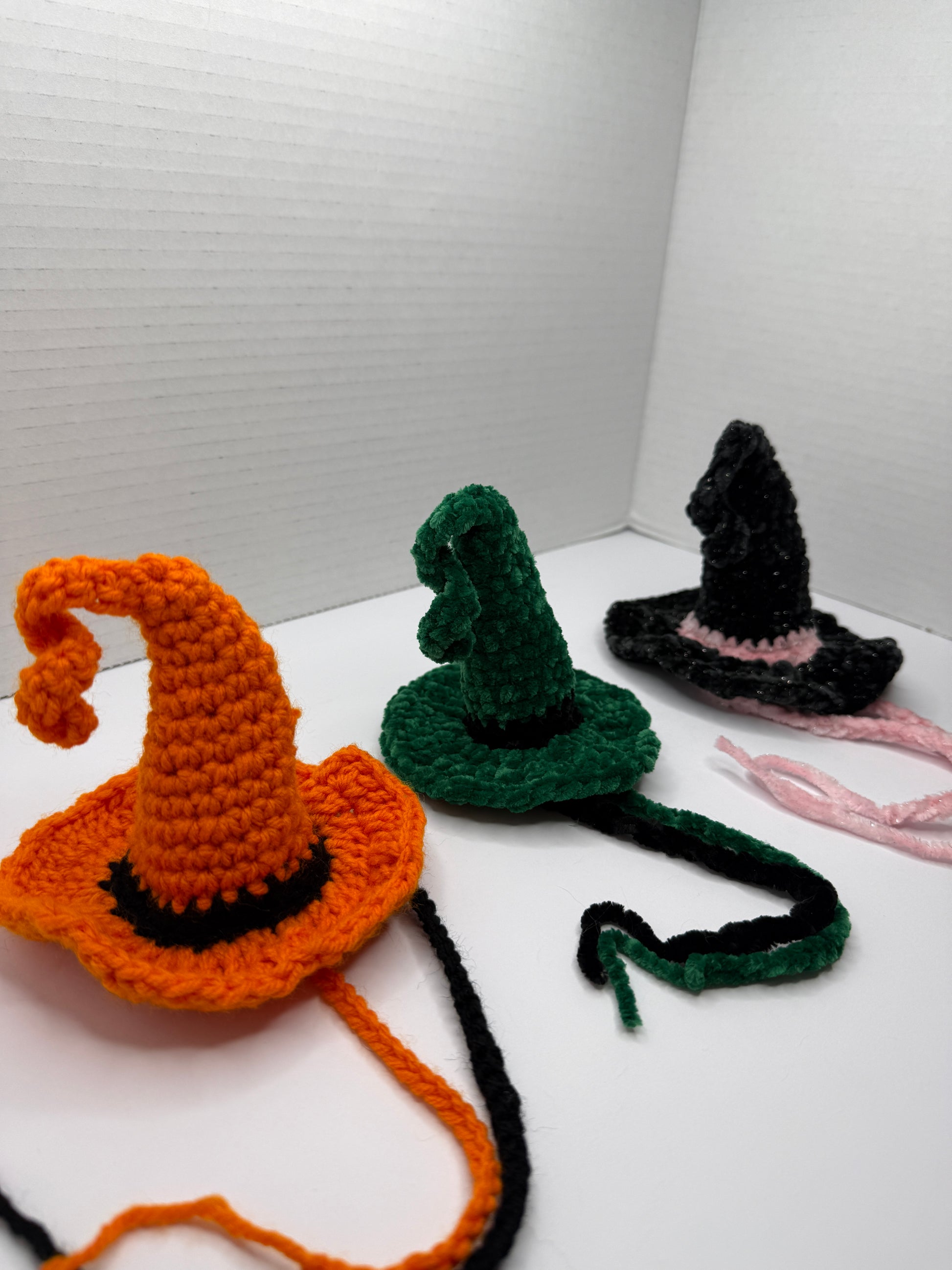 Crochet witch hats for cats in various colors on a white background