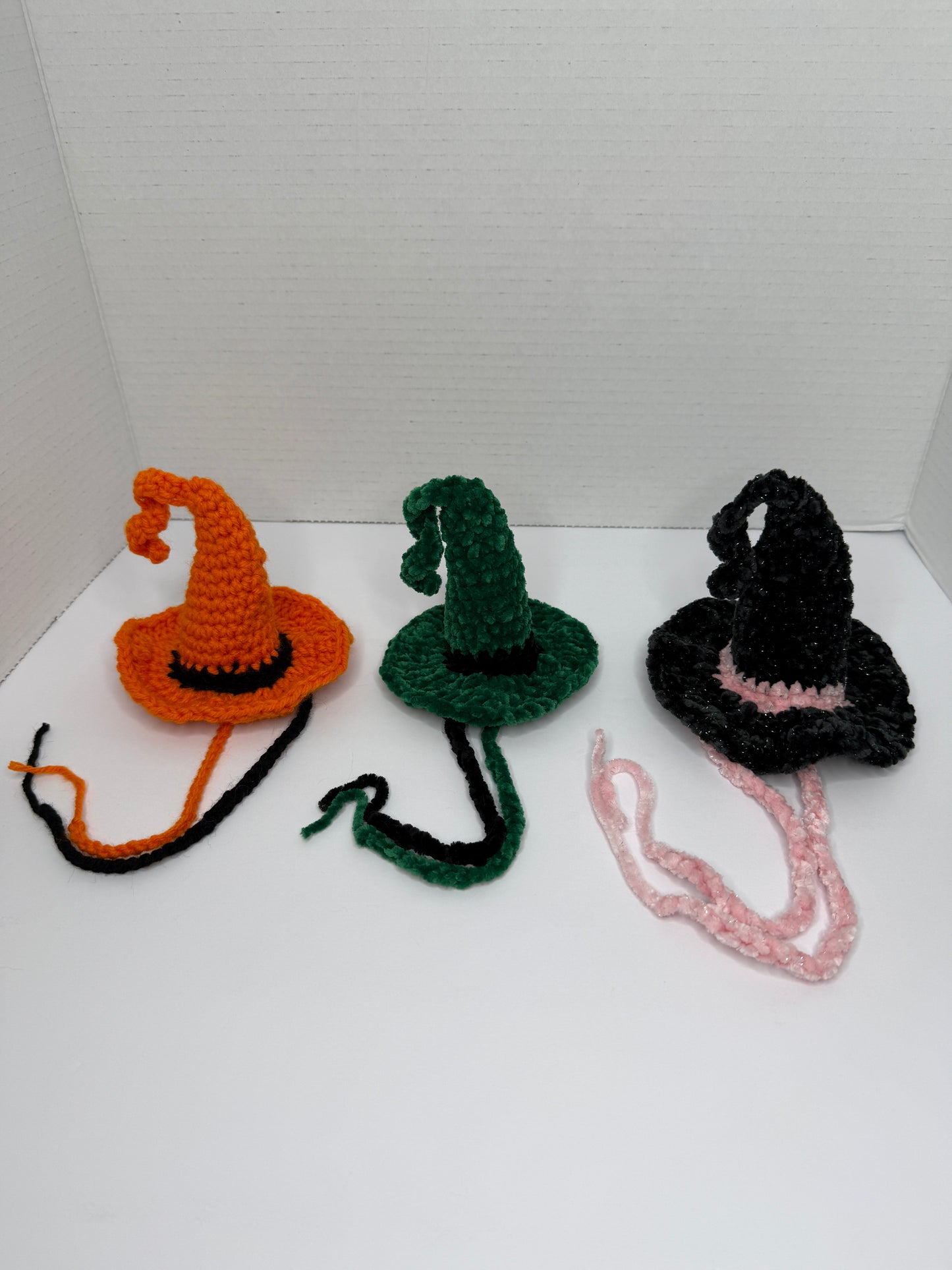 Crochet witch hats for cats in various colors on a white background