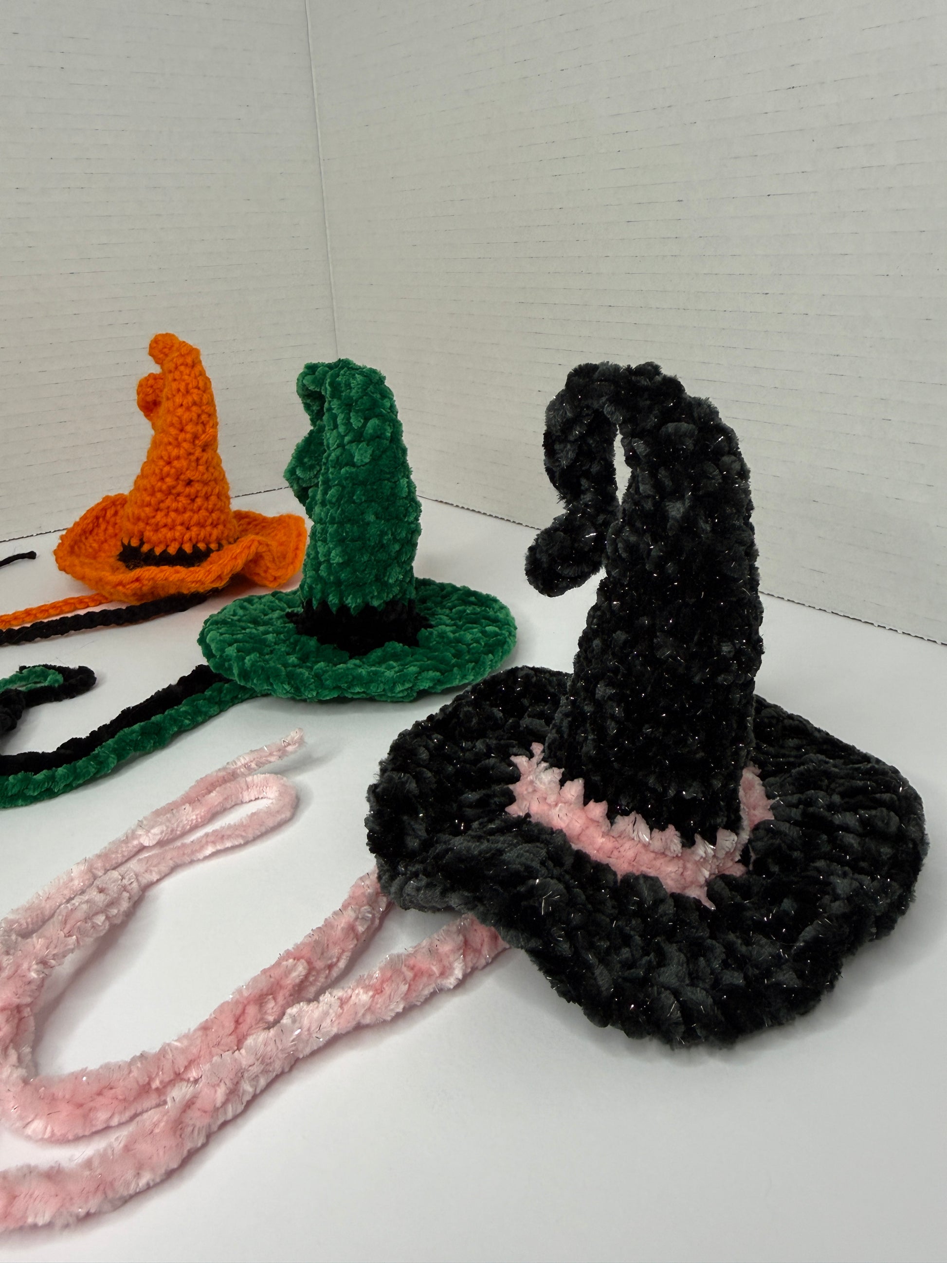 Crochet witch hats for cats in various colors on a white background