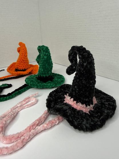 Crochet witch hats for cats in various colors on a white background