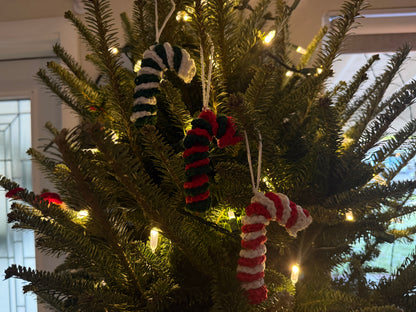 Decorative candy cane ornaments on a Christmas tree with lights.