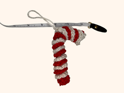 Red and white striped candy cane-shaped keychain with a measuring tape for scale on a white background